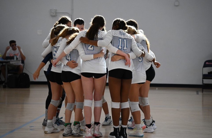 The girls volleyball team huddling together.