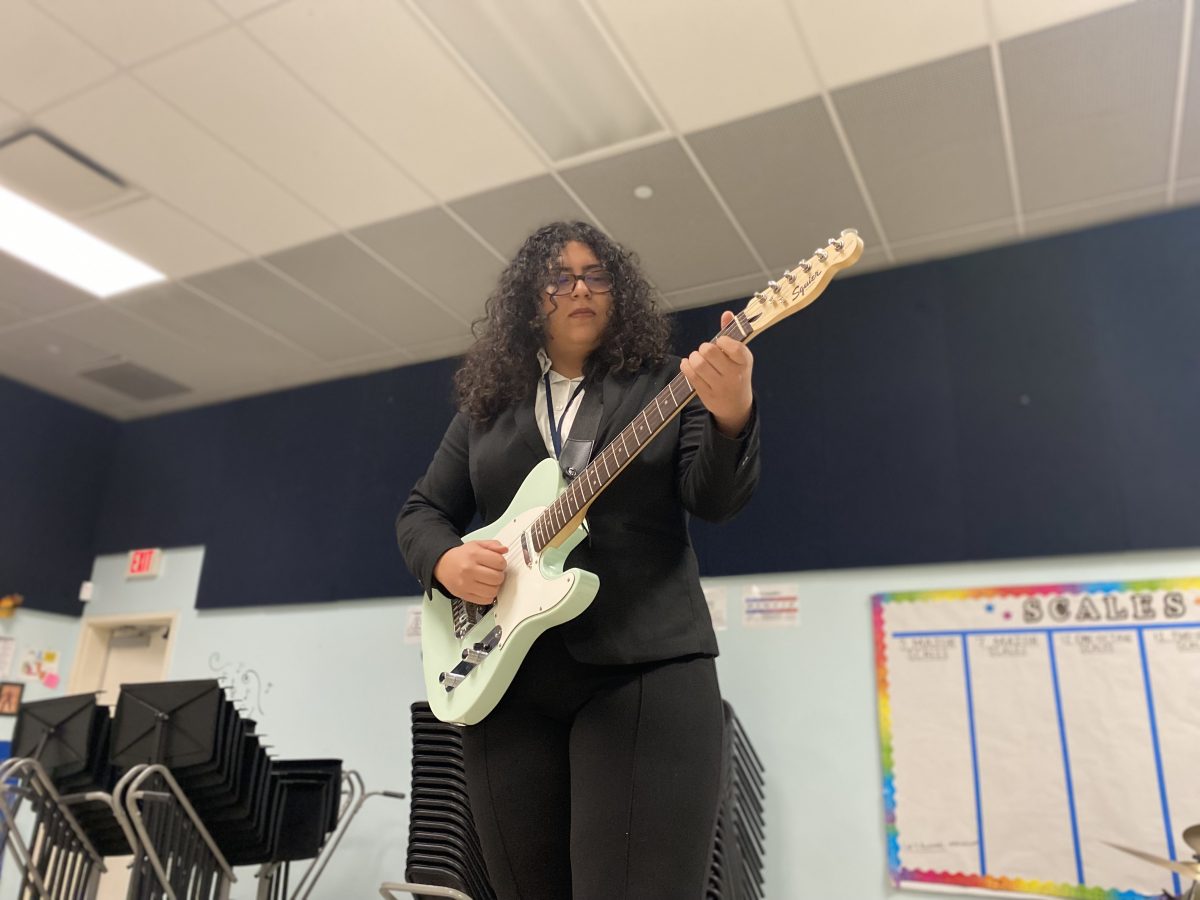 Toline Abdelhafiz playing guitar in the Band Room. Her favorite instrument is the guitar and she uses it to come up with most of her ideas.