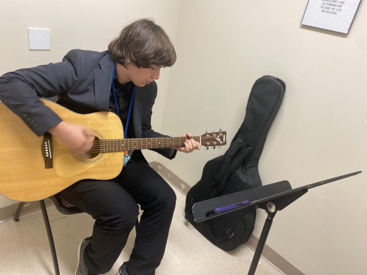 Jacob Head, playing the guitar in a practice room. The guitar was his first instrument and is his favorite.