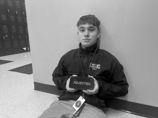 Senior Ty Mainardi holding a phone with the word Rejected plastered on it.