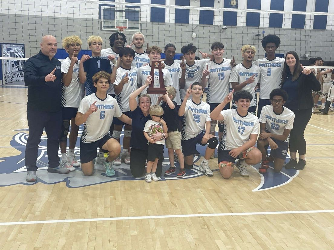 The boys varsity volleyball team gathers together to take a picture with the trophy they received after winning their district match.