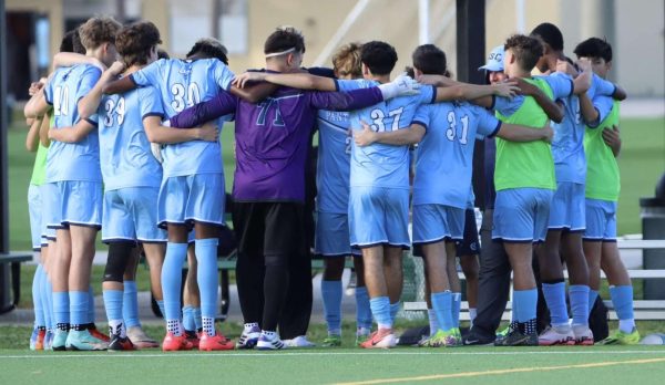 The soccer team huddled up together for a pep talk.