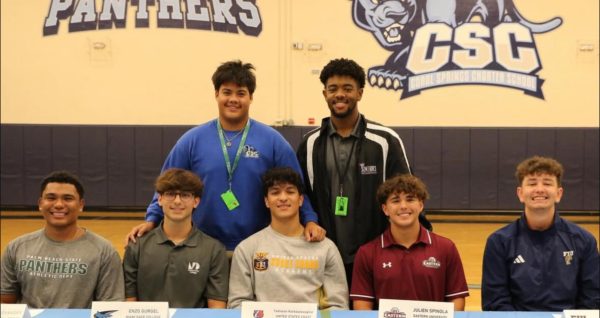 Senior baseball team signing, and teammates supporting their peers.